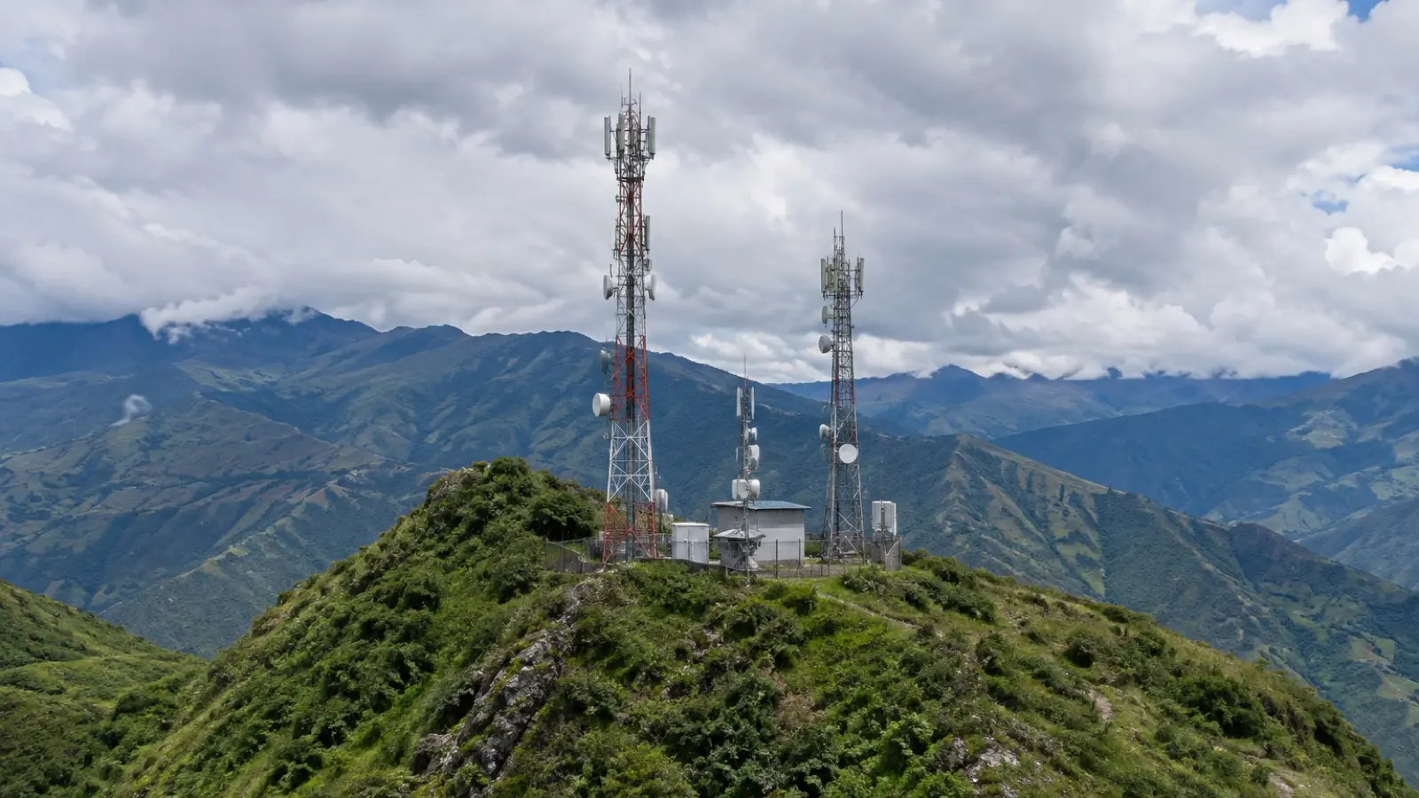 Antenas sobre una loma andina, con cielo nublado