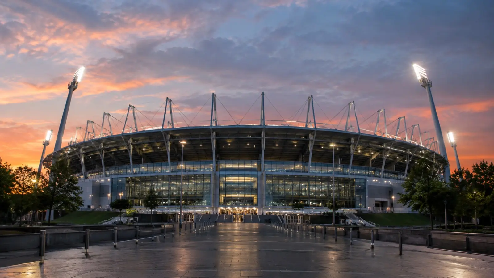 Exterior de un estadio al anochecer, con los reflectores encendidos